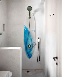 a white bathroom with a blue surfboard hanging on the wall and a shower head