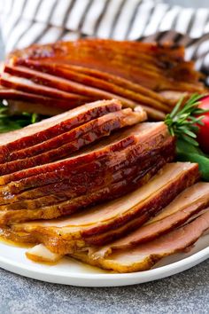 sliced ham on a white plate with tomatoes and lettuce next to the meat