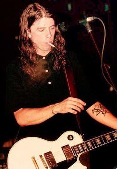 a man with long hair playing an electric guitar