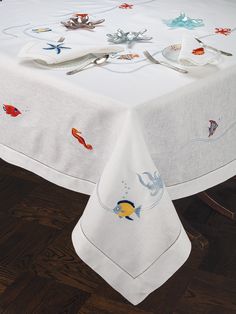 a white table cloth with fish and starfish designs on it, sitting on top of a wooden floor