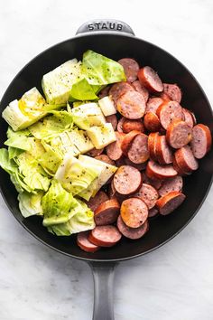 sausage, lettuce and tomatoes in a skillet on a marble countertop