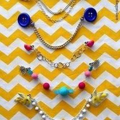 several different necklaces are arranged on a yellow and white chevron tablecloth with blue buttons