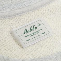 a label on the back of a sweater that says mahlu in green and white