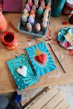 the table is covered with art supplies and crafting supplies, such as paints, paper hearts