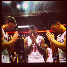 three basketball players applauding each other at a game