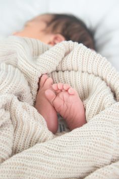 a baby is wrapped in a blanket and laying on it's side with its feet tucked under the blanket