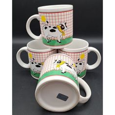 four coffee mugs are stacked on top of each other, with pictures of cows