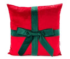 a red pillow with a green ribbon tied around the front and back of it, on a white background