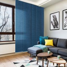 a living room with blue walls and pictures on the wall above the couch, along with two coffee tables