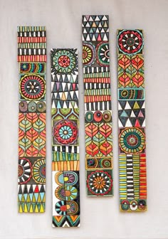 three pieces of art made out of wood with designs painted on the top and bottom