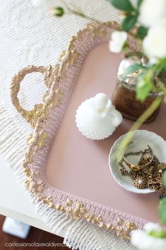 there is a tray with rings on it and flowers in the vase next to it