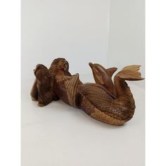 a wooden carved figurine of a mermaid with her tail curled up in the air