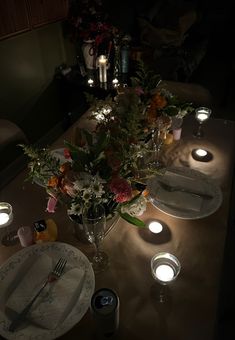 the table is set with candles and flowers in vases, plates and utensils