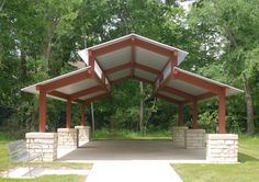 an outdoor covered area with benches and trees in the background