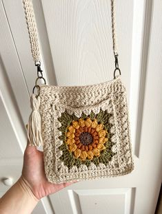 a hand holding a crocheted purse with a sunflower on it