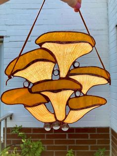 a stained glass lamp hanging from the ceiling in front of a brick building with green plants