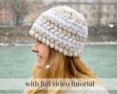 a woman with long blonde hair wearing a white knitted beanie hat in the snow