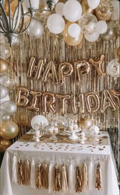 a birthday party with gold and white balloons, streamers, tassels and confetti