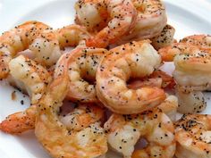 some shrimp on a white plate with black pepper sprinkled on it and seasoning