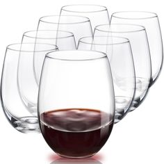 six wine glasses with red liquid in them on a white surface, set next to each other