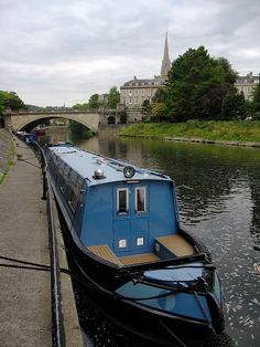 a blue and black boat on the water next to a bridge