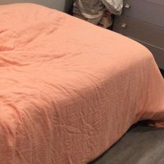 a bed sitting next to a dresser with a basket on top of it