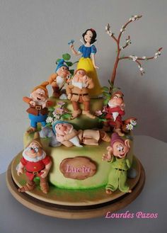 a cake with snow white and the seven dwarfs on it's top is sitting on a table