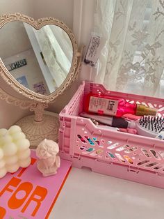 a pink container with various items in it next to a mirror and other things on the table