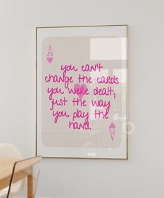 a pink quote on a white wall above a wooden table