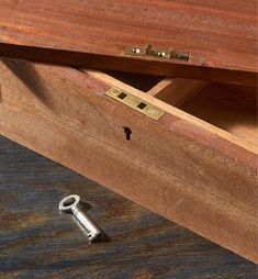 an open drawer with a key in it on the floor next to a wooden table