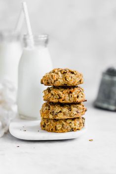 three oatmeal cookies stacked on top of each other with a glass of milk in the background