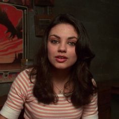 a woman sitting at a table with food in front of her and an eagle on the wall behind her