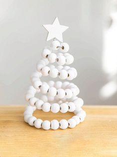 a white beaded christmas tree sitting on top of a wooden table next to a star