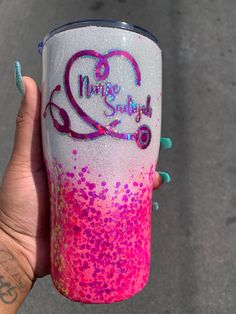 a hand holding a pink and white cup with purple sprinkles on it