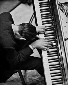 a man sitting at a piano with his hands on the keys and head resting against it