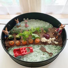 a pot filled with plants and toys on top of a table