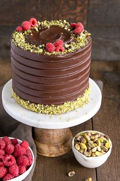 a chocolate cake with raspberries and pistachios on the top is surrounded by other dessert items