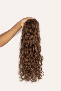 Our Light Brown curly clip-in hair extensions feature subtle ash tones and are ideal for hair that’s between medium blonde and dark brown. This shade beautifully complements cool tones. Our Curly Style clip-ins are perfect for those with a 3B texture, in between a loose wave and curly texture. Our 220-gram set is for those who already have medium or thick hair and are looking to add length or have an extra voluminous look. This is the set that we recommend for those with short hair looking to ad Curly Drawstring Ponytail, Curly Human Hair Extensions, Curly Clip Ins, Curly Ponytail, Drawstring Ponytail, Curly Hair Extensions, Haircut Designs, Medium Blonde, Ponytail Hair Extensions