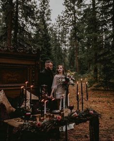 a man and woman standing next to each other in front of a table with candles