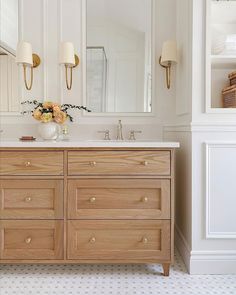 a bathroom vanity with two sinks and large mirrors on the wall above it is decorated with flowers