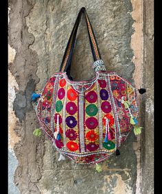 a colorful handbag hanging on the side of a stone wall