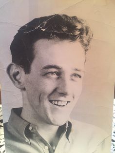 an old black and white photo of a man with short hair smiling at the camera