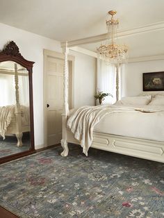 a large white bed sitting in a bedroom on top of a blue and green rug