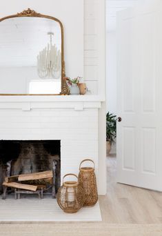 a white fireplace with a mirror above it and two wicker baskets next to it