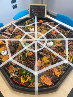 a table that has been decorated with leaves and pineconis in the shape of a hexagon