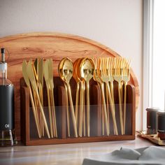 gold colored spoons and forks in a wooden holder