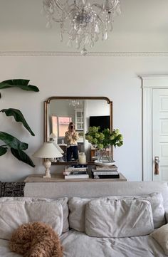 a living room filled with furniture and a chandelier hanging from the ceiling next to a mirror