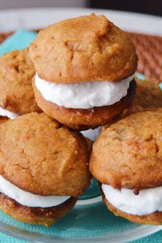 four cookies with white frosting are stacked on a glass plate