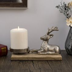 a silver deer figurine sitting on top of a wooden table next to a candle