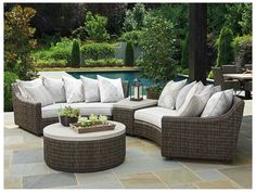 an outdoor furniture set with pillows on the couch and coffee table in front of a pool